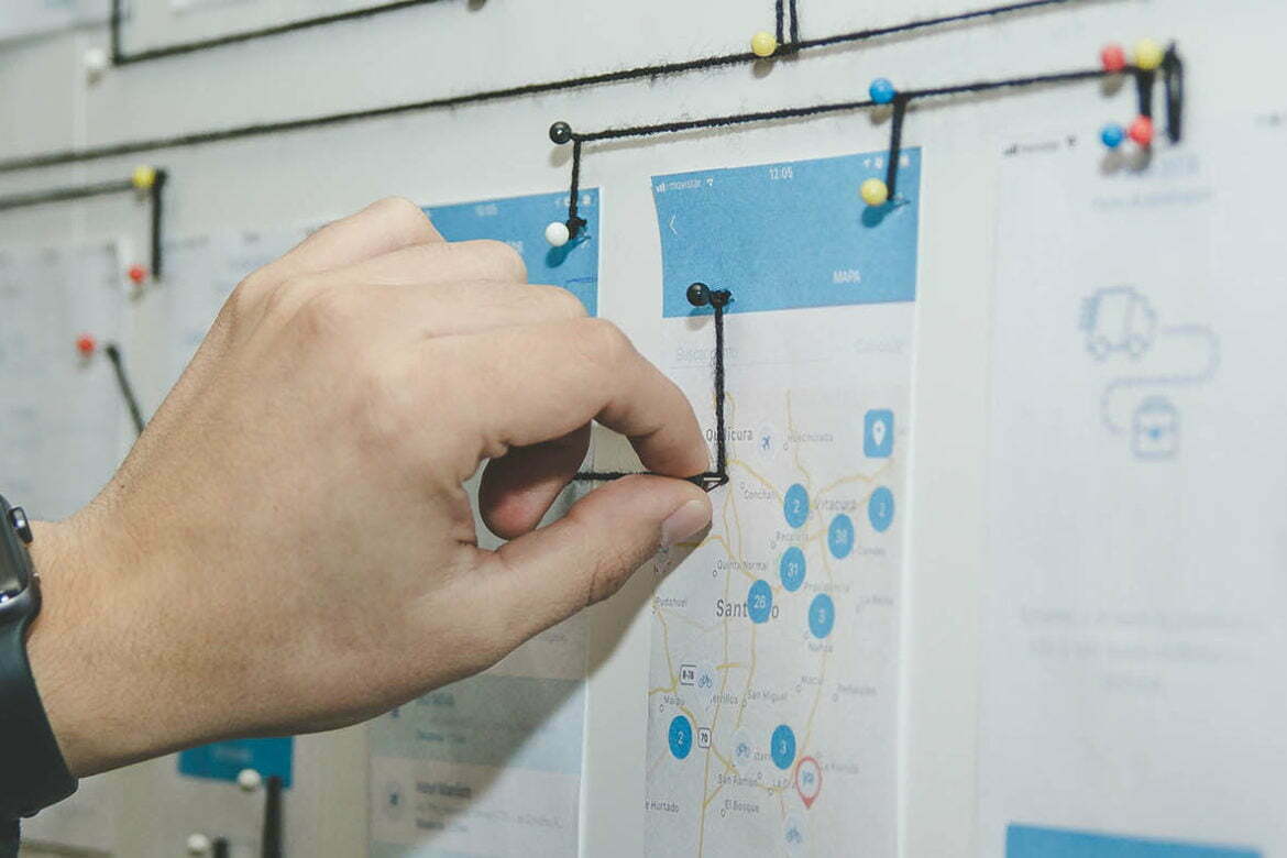 A close up photo of many webpages pinned to a board, with a person using string to connect the pins, indicating how the webpages are connected together on the entire website. This is an image relating to the tutorial article: How to create a sitemap